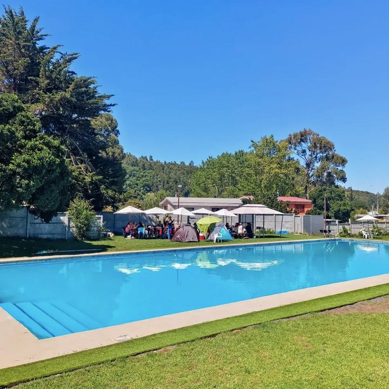 Piscina al aire libre con quitasoles y césped en un día soleado