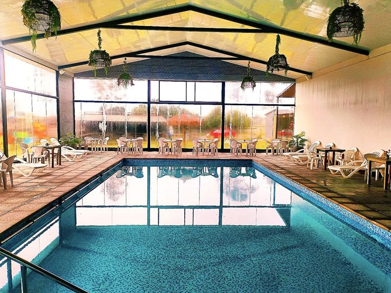Piscina temperada techada, con ventanales y mesas alrededor