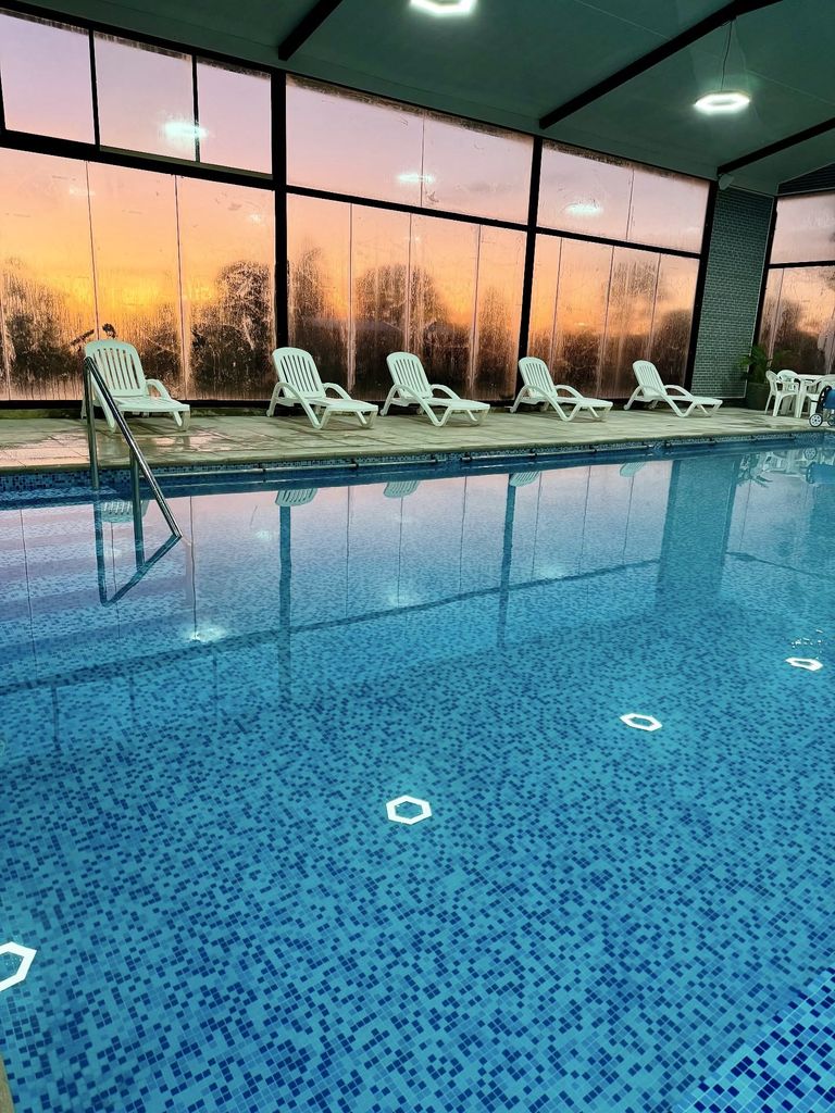 Piscina temperada con reposeras junto a los ventanales